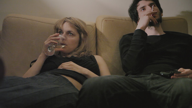 An exhausted young couple sits on a couch.