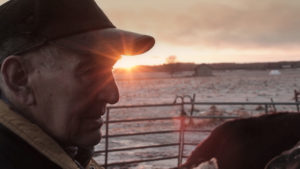 Das Gesicht eines alten Mannes im Profil vor einem Sonnenuntergang im Winter