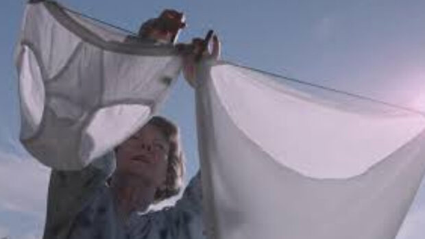 Eine Frau im Morgenrock hängt Wäsche auf