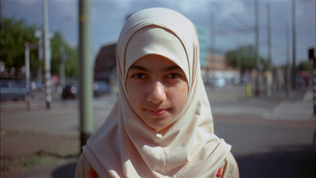 Frontansicht von einem Mädchen, die ein Hijab trägt. Im Hintergrund snd Strassenverkehr.